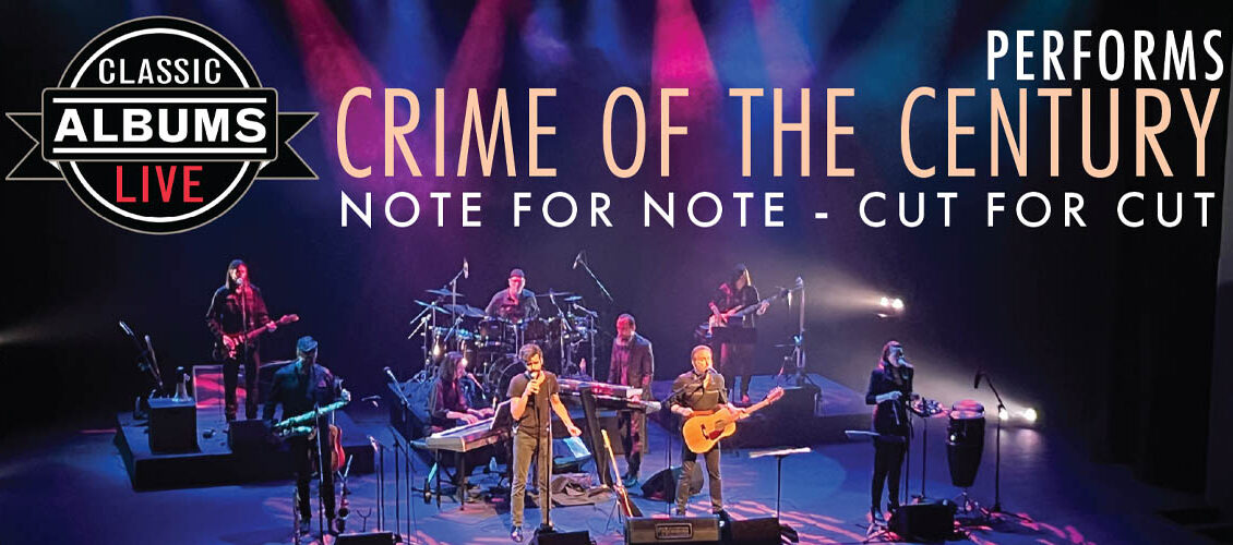 The Classic Albums Live band perform on a stage lit with purple and pink lighting. Everyone is dressed in black. Someone is singing into a microphone.